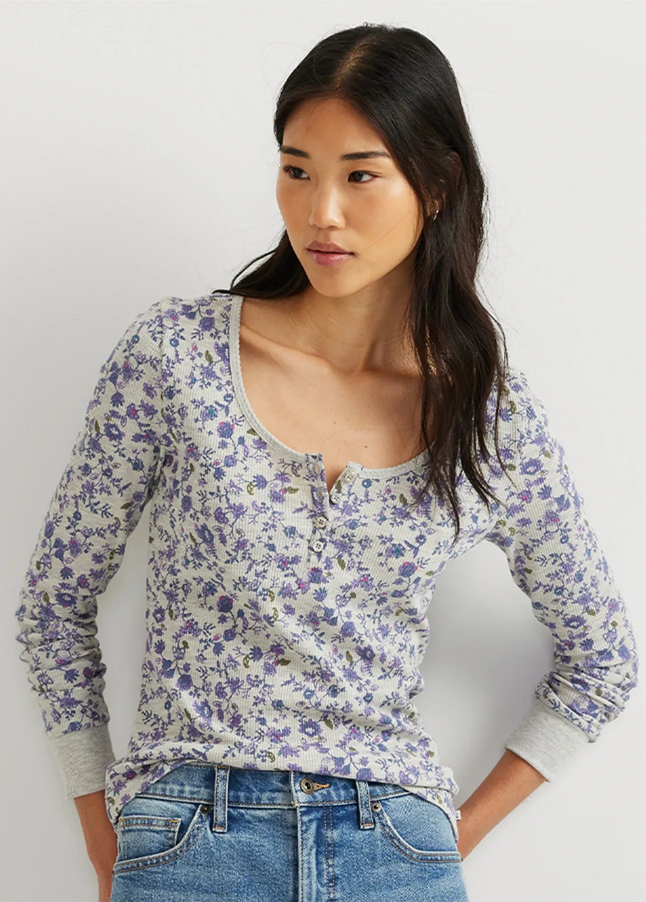 A woman wearing a thermal top with a floral pattern and jeans.