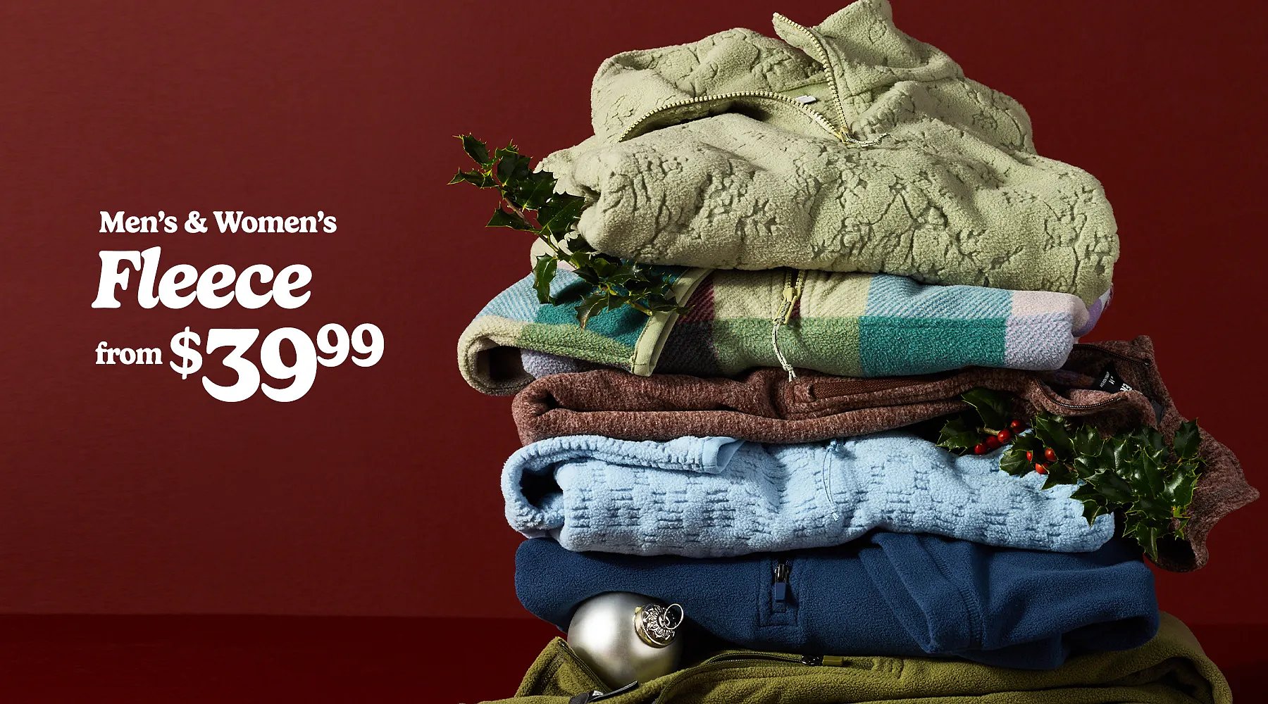 Men’s & women’s fleece from $39.99. A stack of folded fleece styles decorated with holly sprigs & a Christmas ornament.
