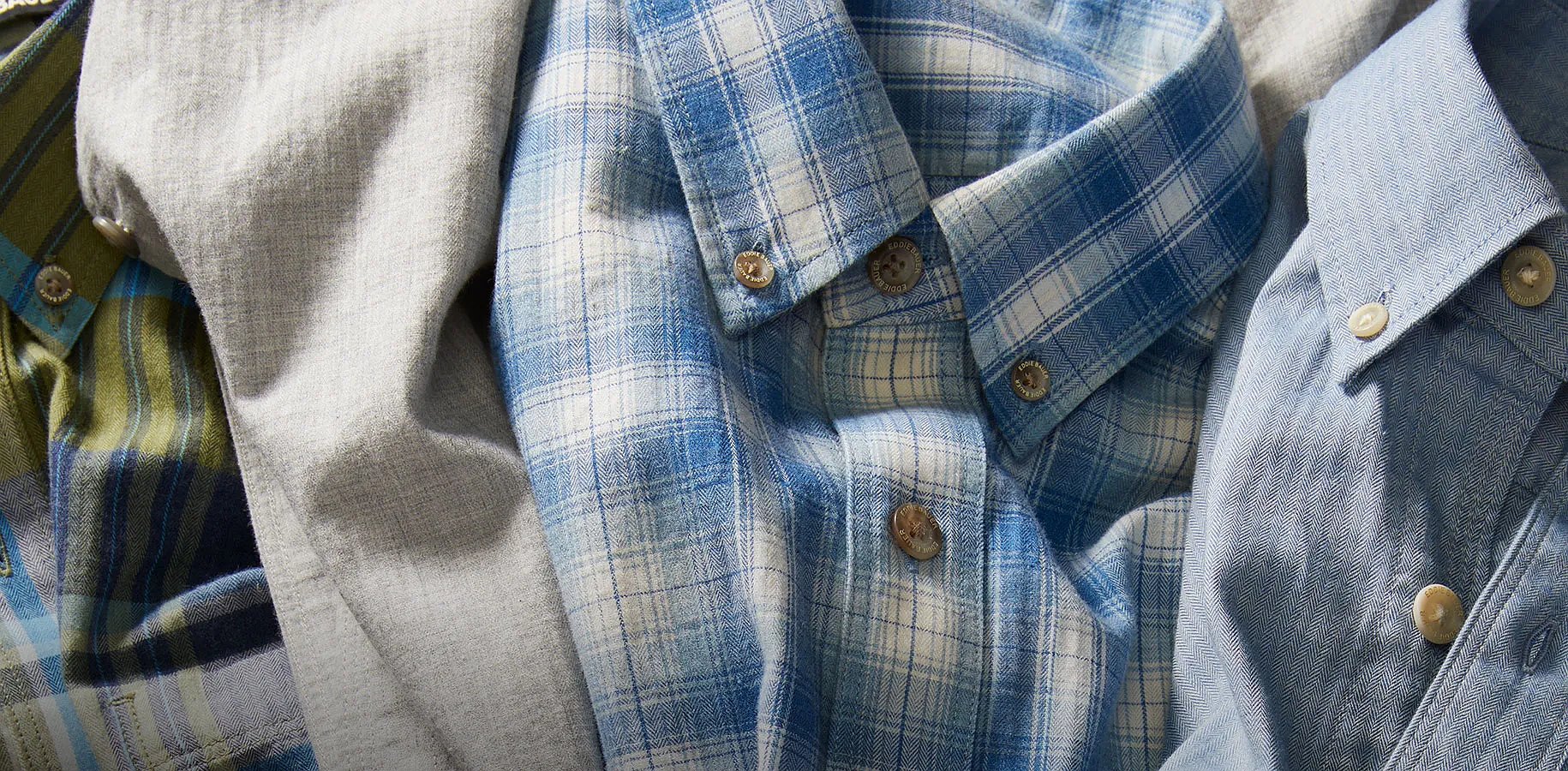 A man and a woman both wearing lightweight plaid shirts layered over a T-shirt.