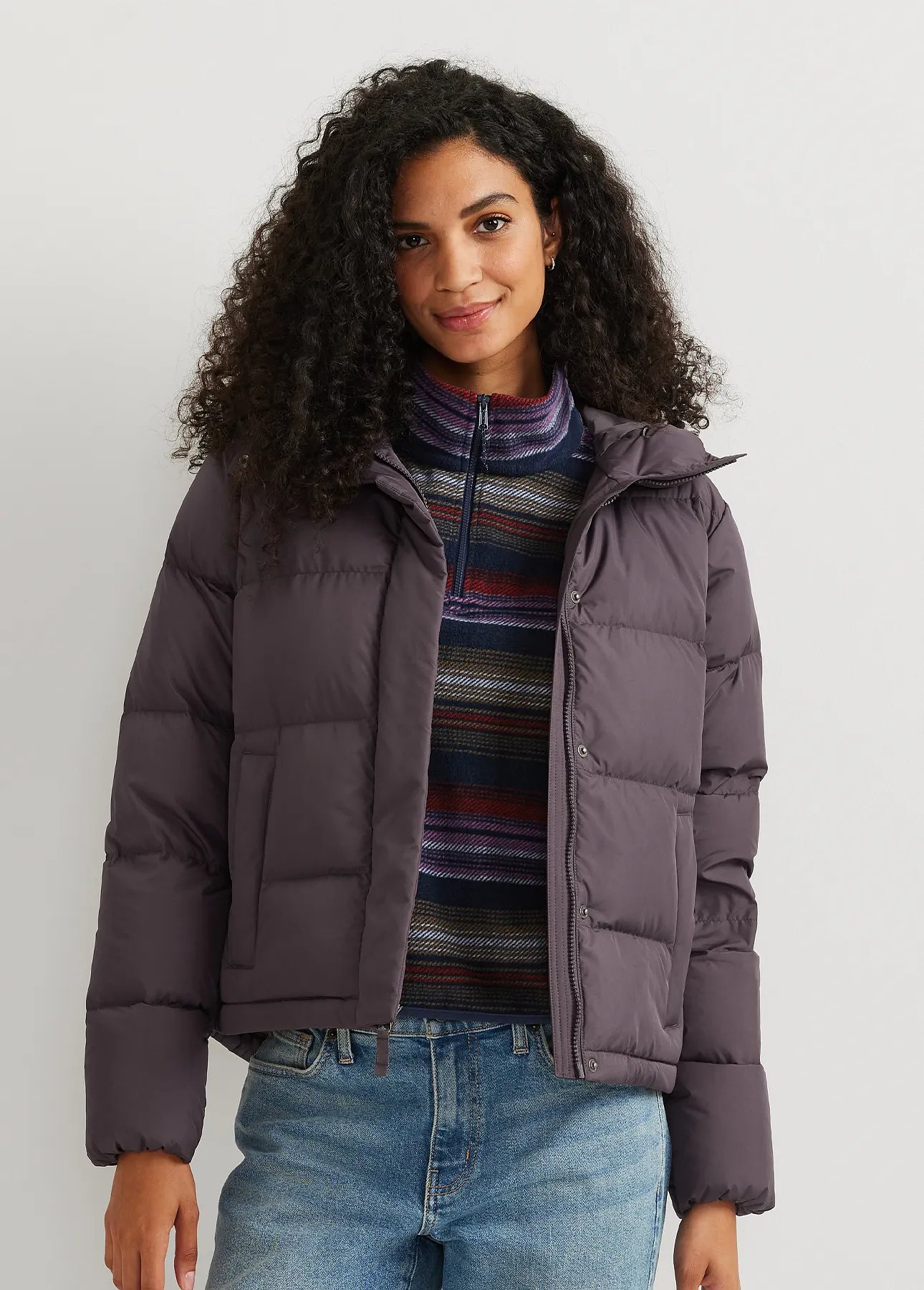 A woman wears an unzipped down jacket over a fleece pullover.