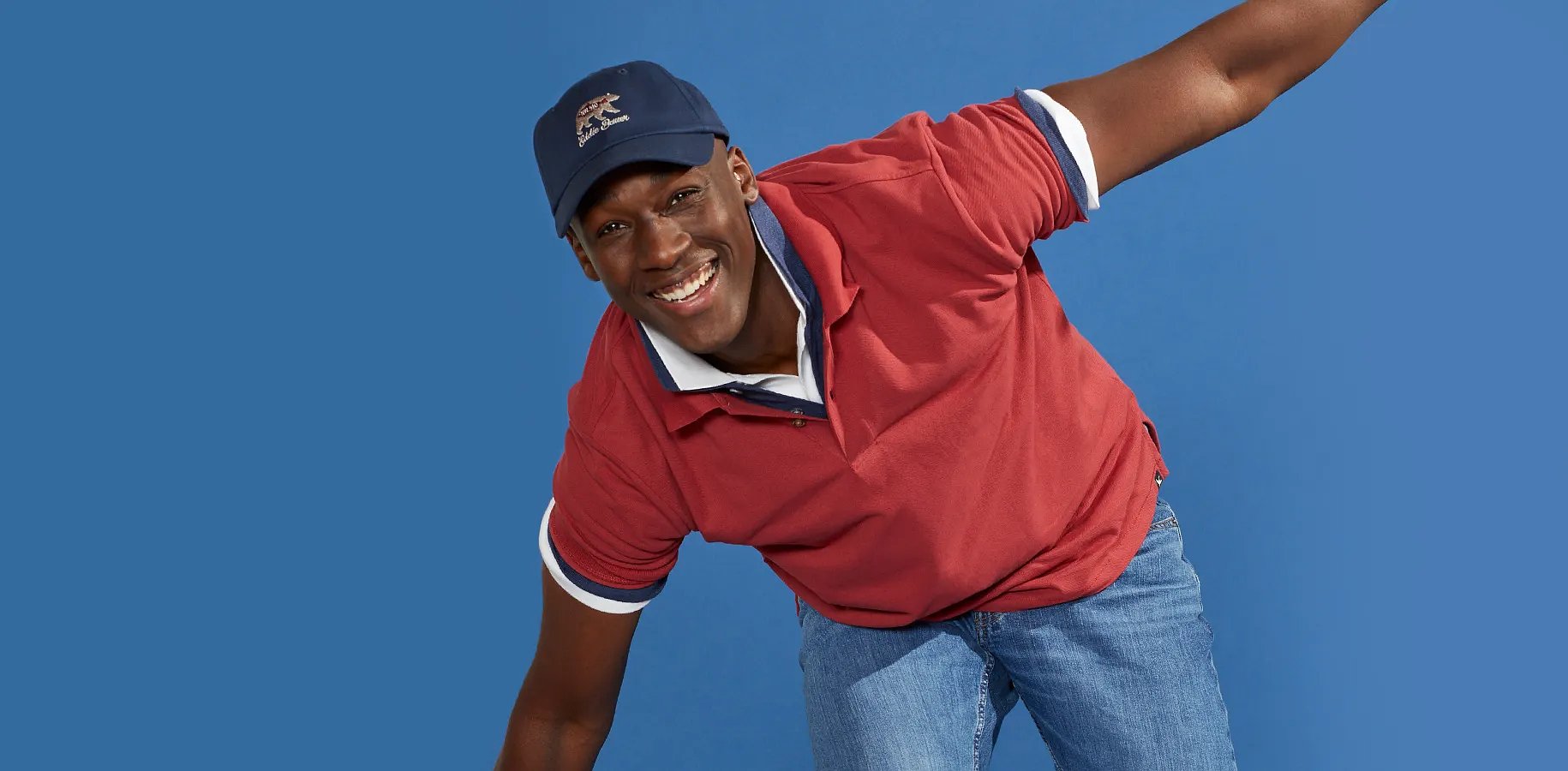 A smiling man with his arms stretched against a blue background