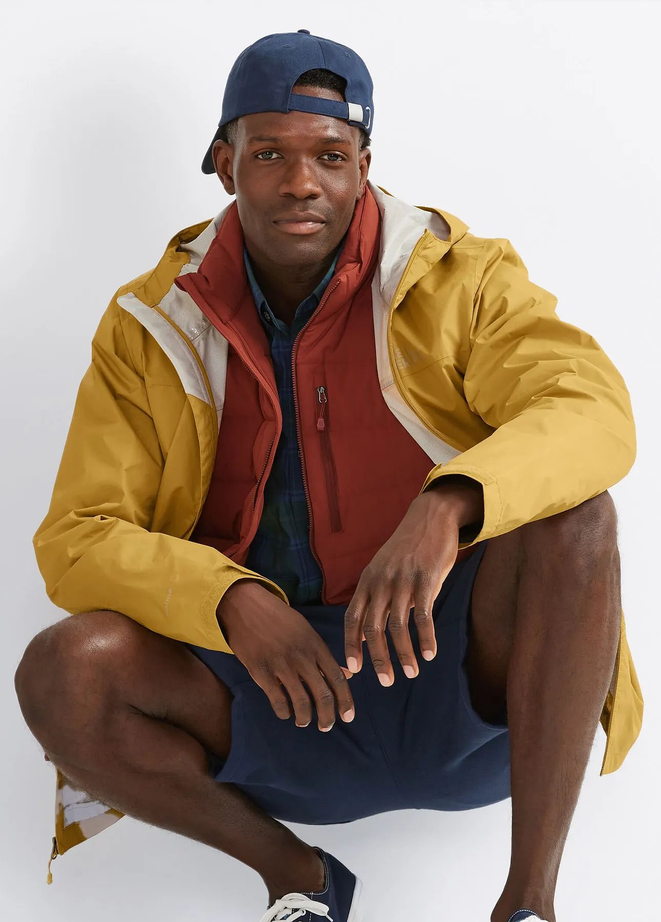 A man wearing a baseball cap and a rain jacket.