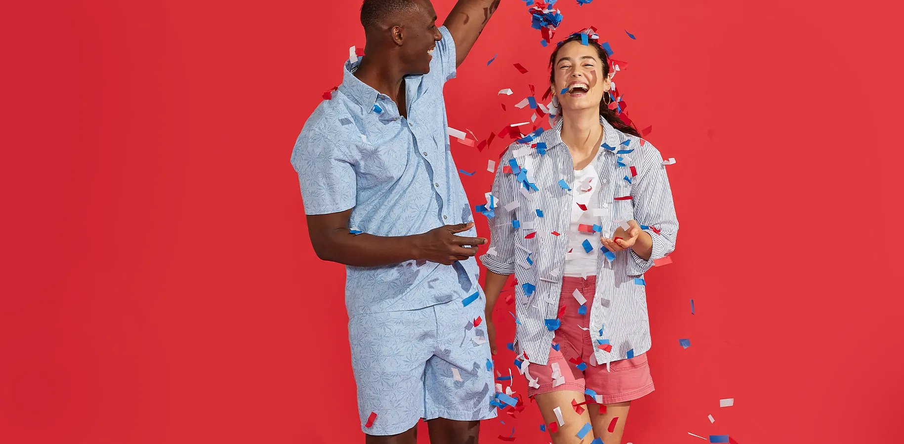 A man and a women playing with confetti against a red background