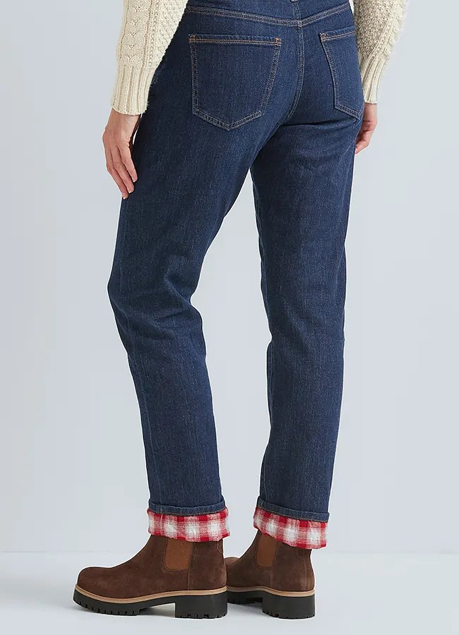 A woman pairs her flannel-lined jeans with boots and rolls up the hem to show the plaid lining.