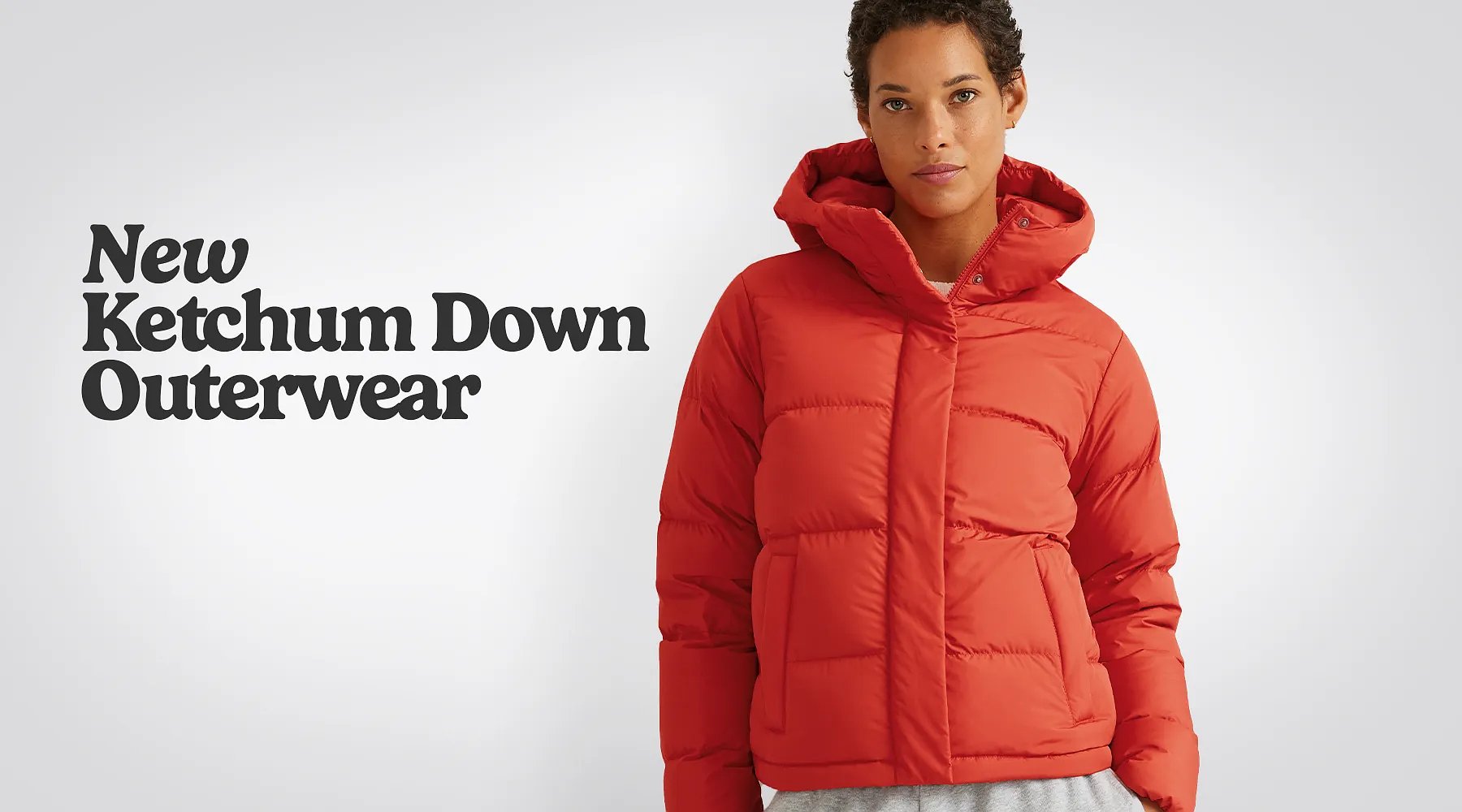 New Ketchum Down Outerwear. A woman with long, curly hair wears a red down jacket.