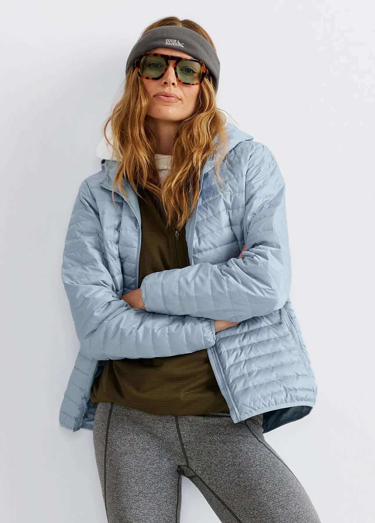A woman wearing a headband, sunglasses and a lightweight down jacket.
