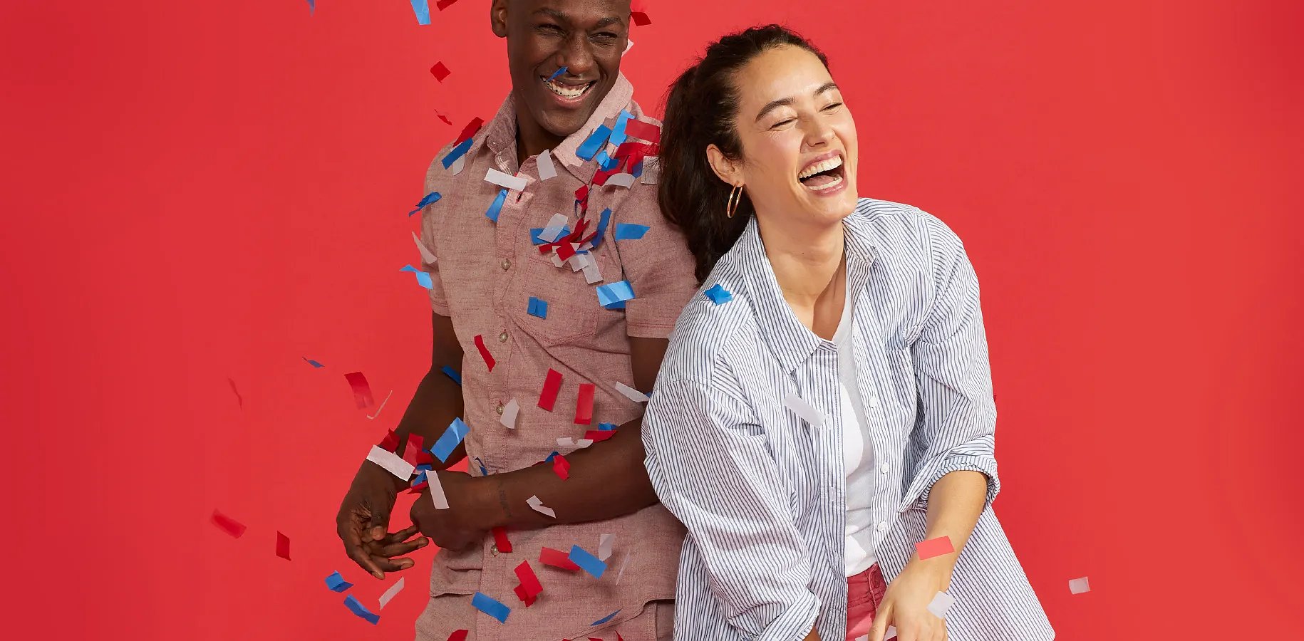 A man and a women playing with confetti against a red background