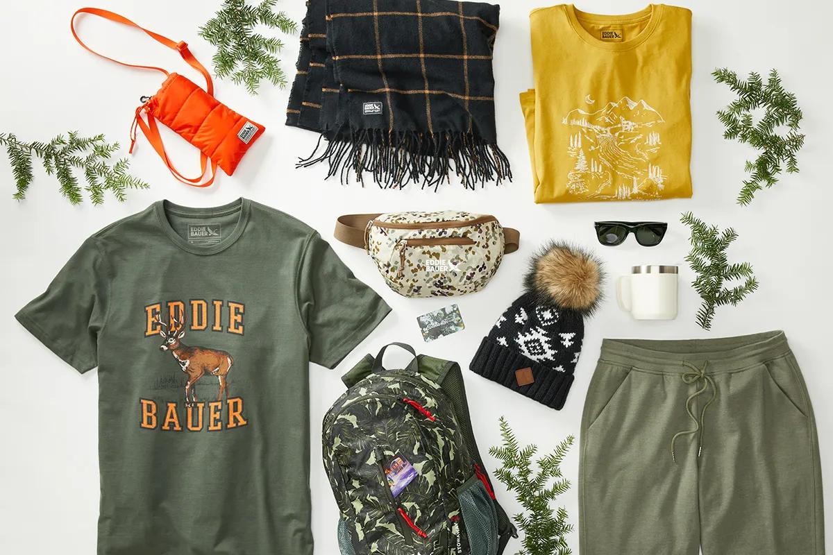 An assortment of apparel and accessories curated around pine branches in a winter holiday inspired theme